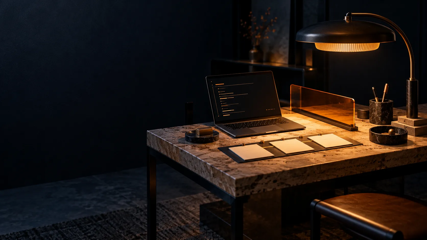 A warm desk lamp beside a laptop in a quiet workspace.
